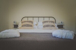 A neatly made bed with two decorative pillows, a bedside table with a lamp, and a wall socket. - Casa Ziazì (Monopoli)