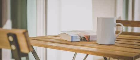A wooden table with a white mug and a book titled "John Steinbeck" and "Pian della".