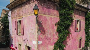 Ein pinkfarbenes Gebäude mit einem Schild mit der Aufschrift 'LA PETIT TABLE', einer Straßenlaterne und Blumentöpfen.