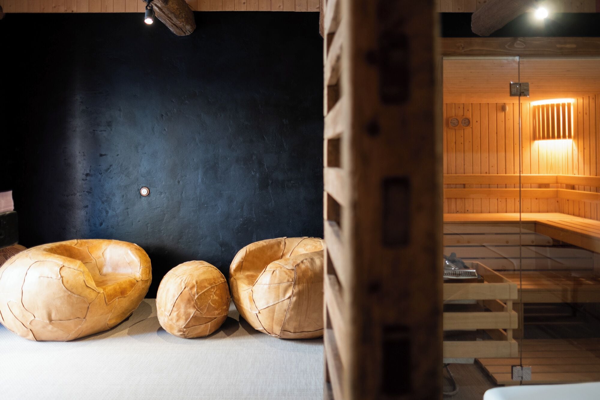 A sauna room with wooden benches and a black wall.