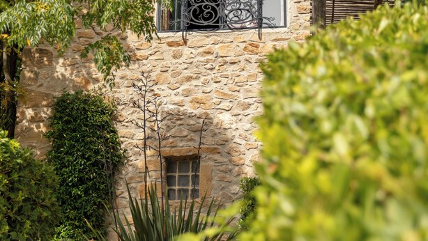A stone building with a window and balcony, surrounded by greenery. - Village Castigno - Wine hotel & resort (Assignan)