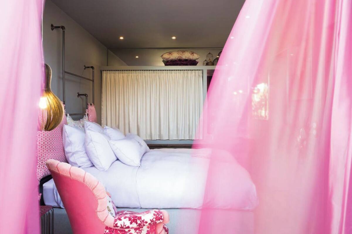A bedroom with a bed, a chair, a lamp, and a window with curtains.