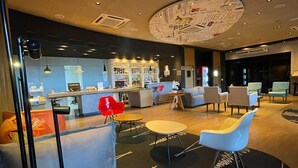 Un vestíbulo moderno con zona de bar, disposición de asientos y un diseño de techo llamativo.