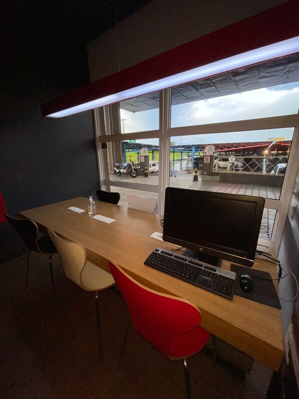 Una habitación de hotel con un escritorio de madera, una computadora y una silla.