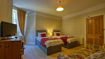A hotel room with two beds, a television, a sofa, and a wooden door.