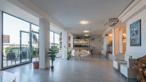 A spacious hotel lobby with a high ceiling, large windows, and a central seating area. - Hotel Blumen (Rimini)