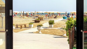 A beachside entrance with a clear view of the beach, umbrellas, and people. - Hotel Blumen (Rimini)