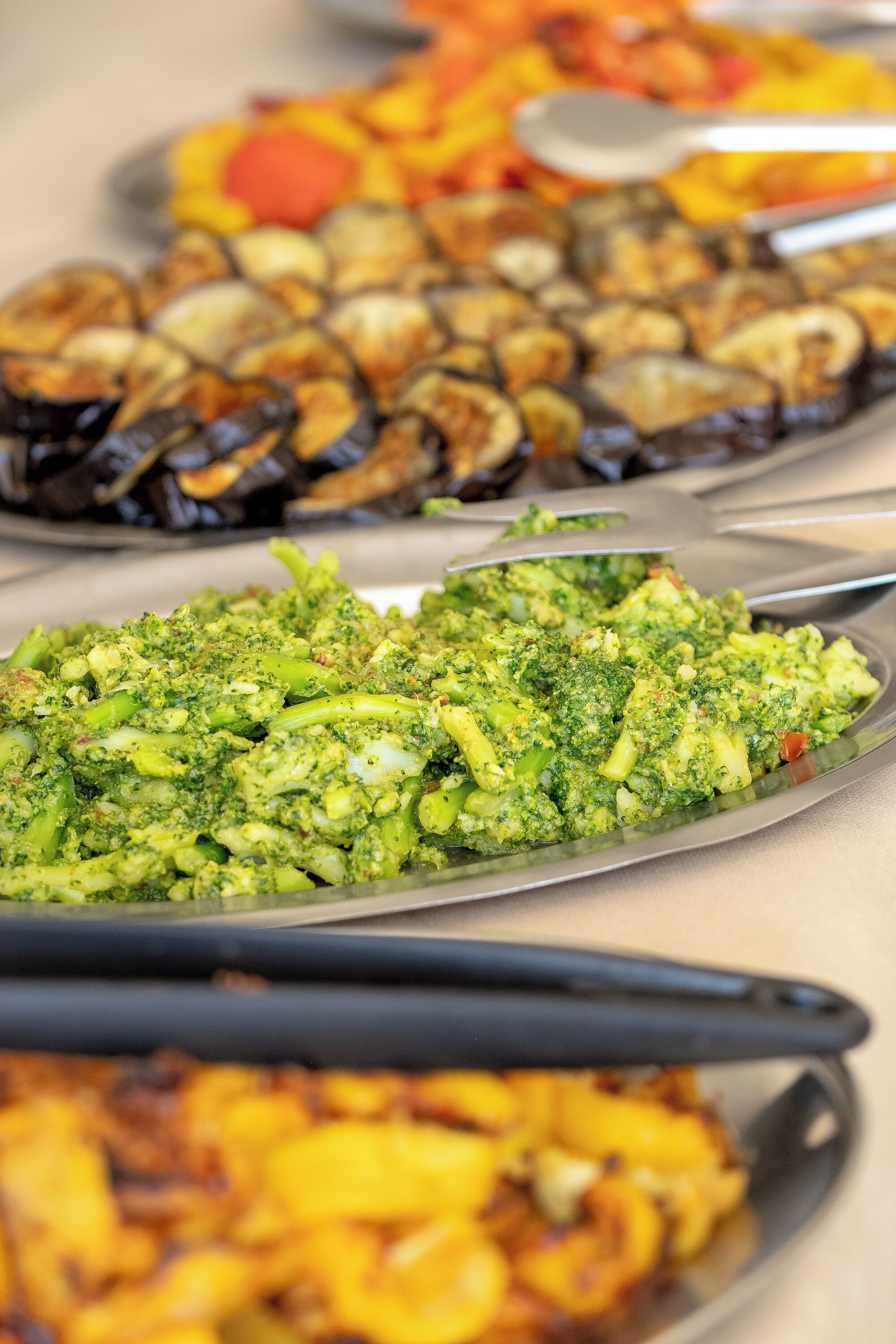 Een buffet met diverse gerechten, waaronder broccoli, champignons en andere groenten.