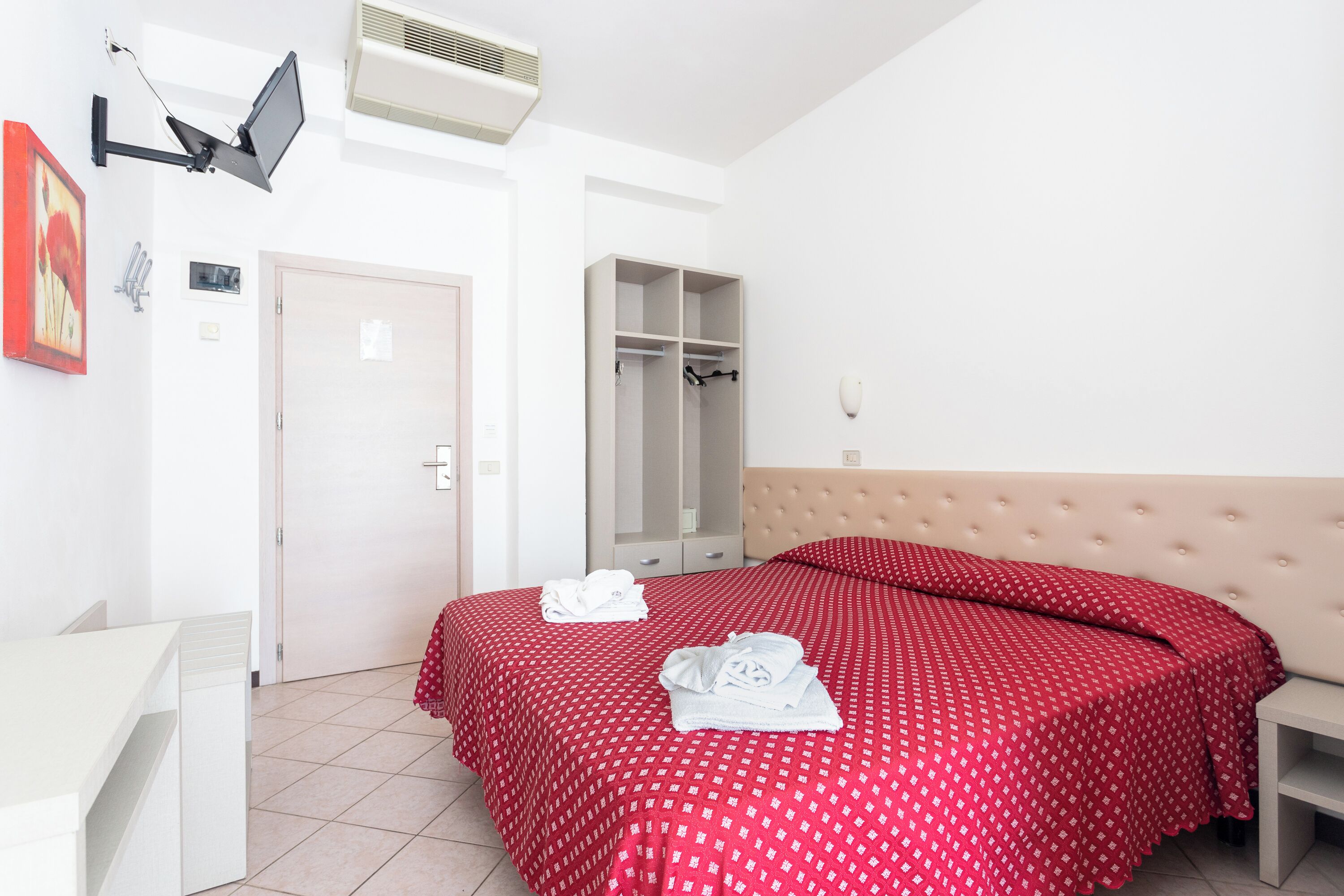 Una camera da letto con un letto, un armadio, un comodino e una scrivania.