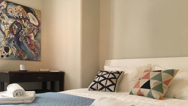 A hotel room with a bed, pillows, a nightstand, a painting, and towels. - Helios (Florence)