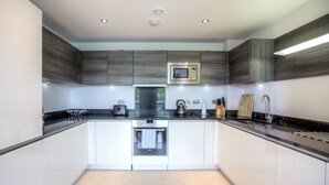 A modern kitchen with white cabinets, a built-in oven, and a microwave.