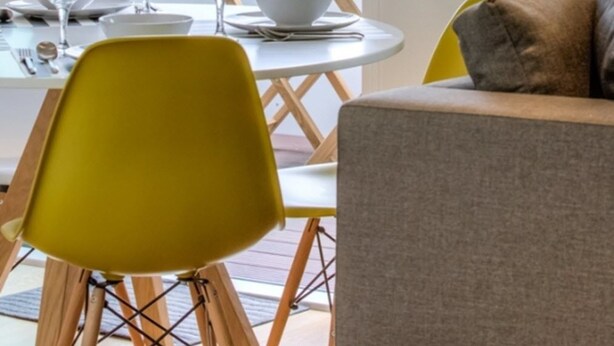 A dining area with a round table, chairs, and a clock on the wall.