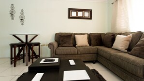 A living room with a sectional sofa, a small dining table with stools, and a coffee table.
