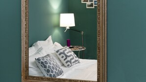 A bedroom with a bed, pillows, a nightstand, a lamp, and a mirror. - Luna (Florence)