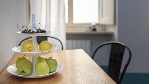 A three-tiered fruit stand with apples and lemons on a wooden table, with a window in the background. - Luna (Florence)