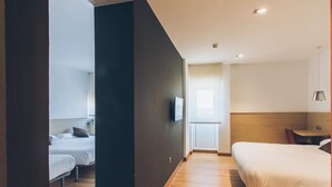 A modern hotel room with a large bed, a smaller bed, and a desk. - Hotel Cadosa (Soria)
