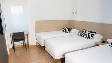 A hotel room with two beds, a desk, and a chair.