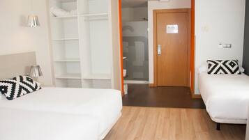 A hotel room with two beds, a wardrobe, and a bathroom.