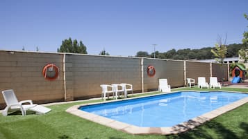 Una piscina al aire libre, sillones reclinables de piscina