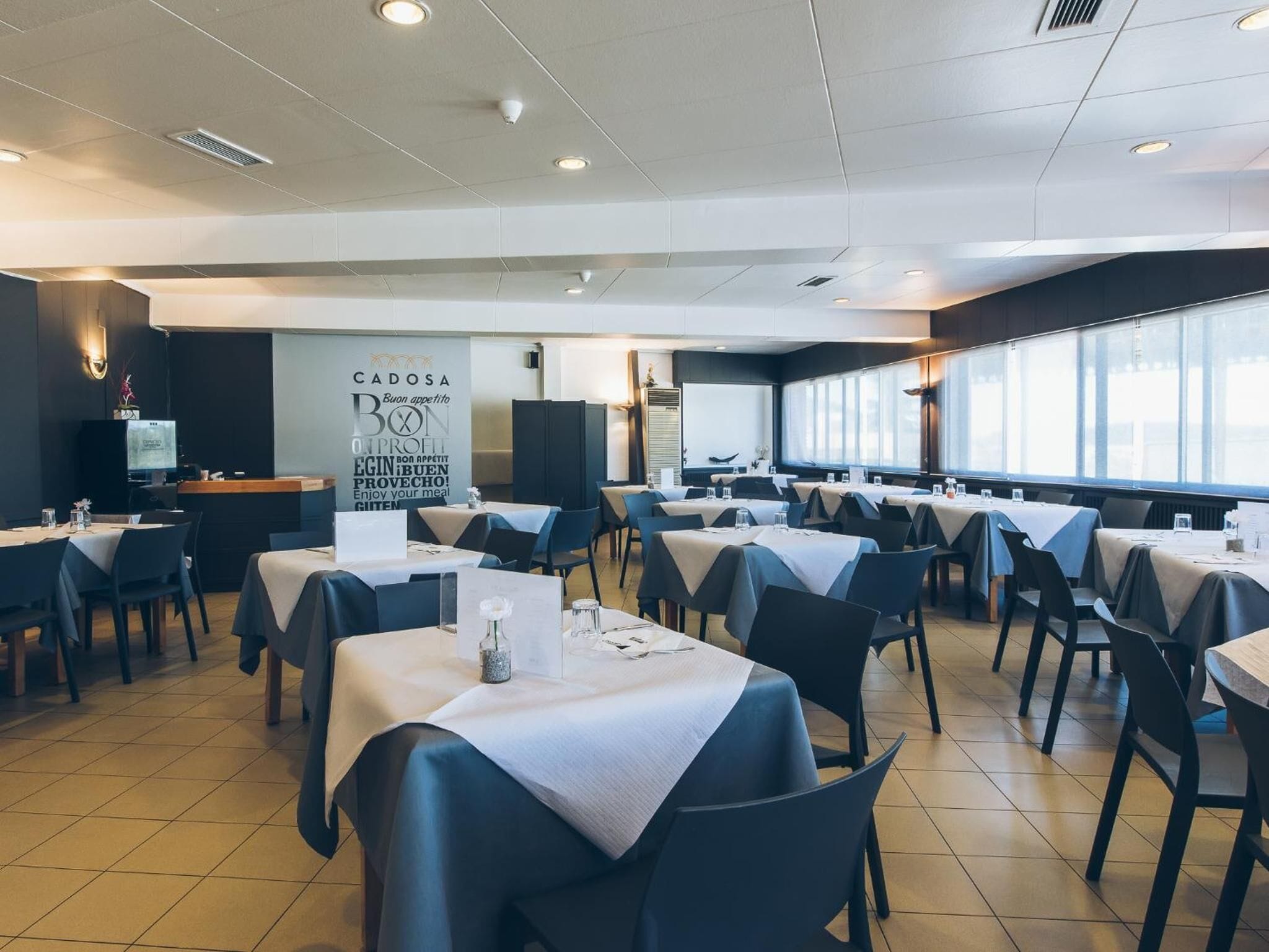 A restaurant with multiple tables and chairs, a large window, and a sign on the wall.