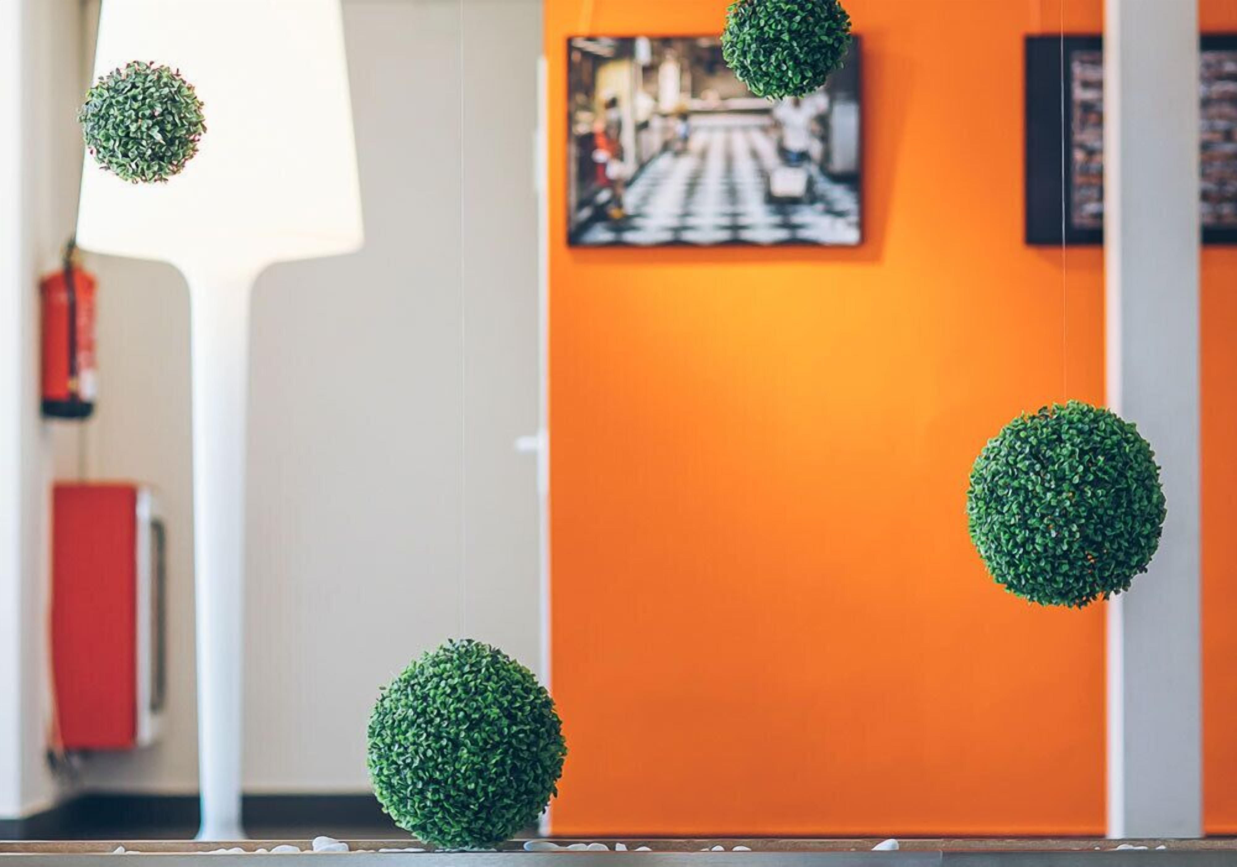 A modern interior with a white column, an orange wall, and a framed picture.