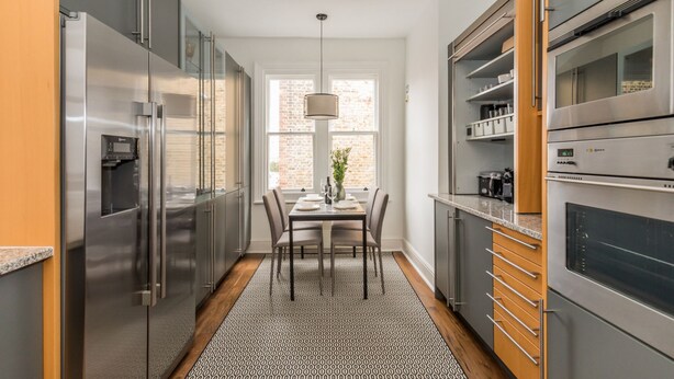 A modern kitchen with stainless steel appliances, a dining table with chairs, and a patterned rug. - Eson2 - Charming 3 Bedroom Flat in Chelsea (London)