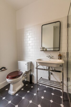 A bathroom with a toilet, sink, and mirror.
