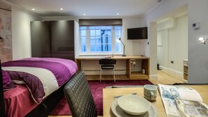 A modern hotel room with a bed, desk, chair, and a window with a view. - Eson2 - The York Street Nest (London)