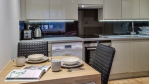 A modern kitchen with a dining area, featuring a dishwasher, a coffee machine, and a sink. - Eson2 - The York Street Nest (London)