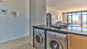 A modern kitchen with built-in appliances, a large window, and a view of the outside. - Atlantic Views 5 (Cape Town)