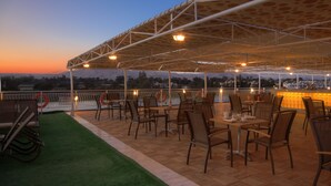 An outdoor restaurant with tables and chairs, a green carpet, and a view of the landscape. - Steigenberger Legacy Nile Cruise - Every Monday 07 & 04 Nights from Luxor - Every Friday 03 Nights from Aswan (Luxor)