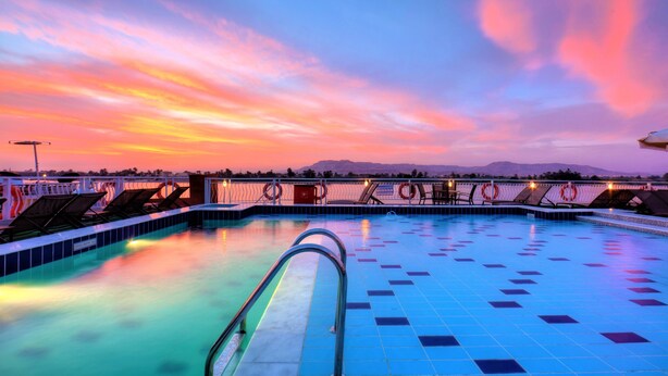 A swimming pool with a view of mountains at sunset. - Steigenberger Legacy Nile Cruise - Every Monday 07 & 04 Nights from Luxor - Every Friday 03 Nights from Aswan (Luxor)