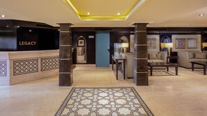 A lobby with a reception desk labeled "LEGACY," a blue door, and a seating area with sofas and a coffee table. - Steigenberger Legacy Nile Cruise - Every Monday 07 & 04 Nights from Luxor - Every Friday 03 Nights from Aswan (Luxor)