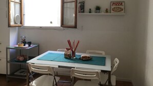 Uma área de refeições com uma mesa, cadeiras, uma janela e um letreiro de pizza na parede.