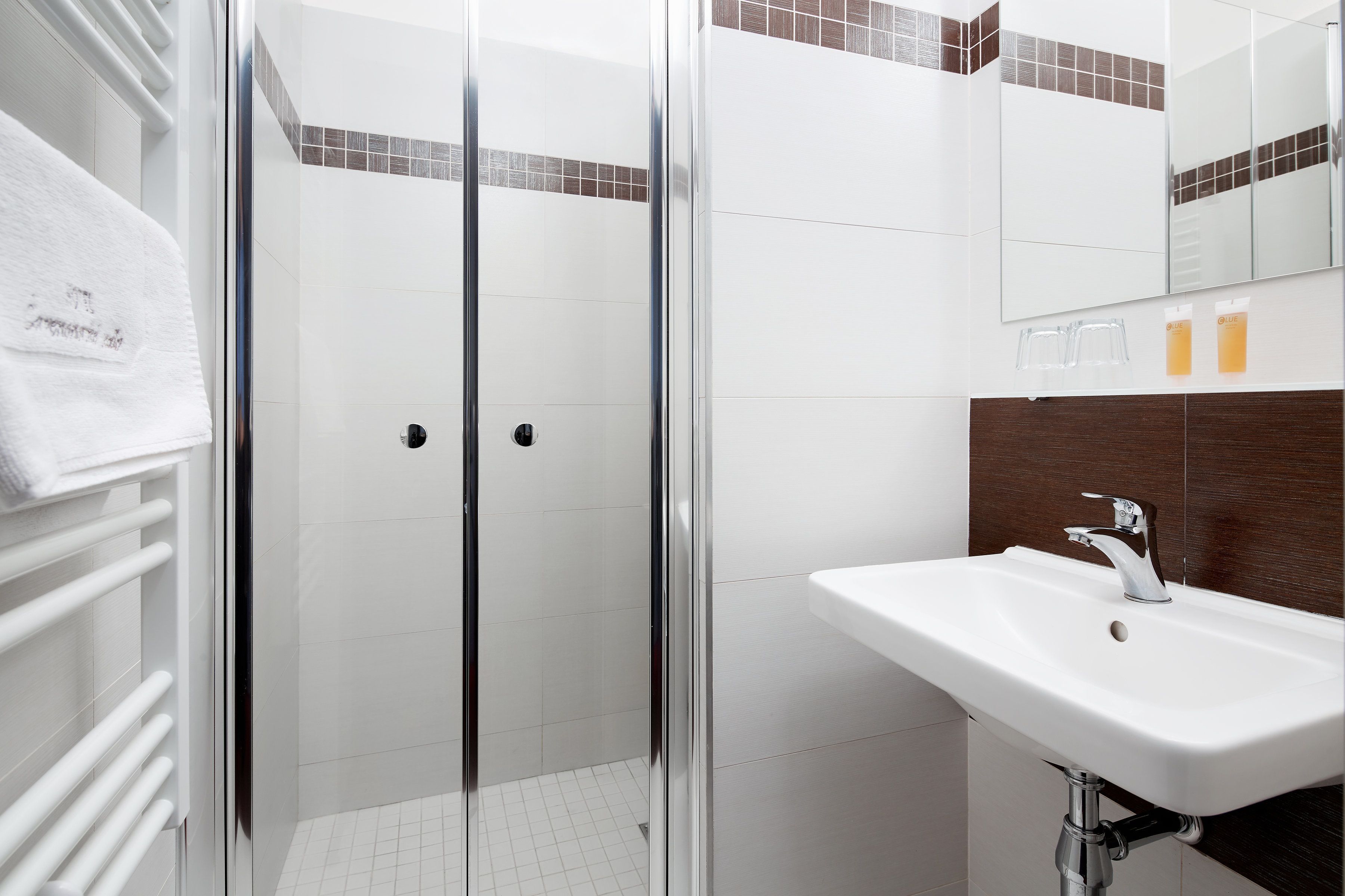A modern bathroom with a glass-enclosed shower, a white sink, and a mirror above it.
