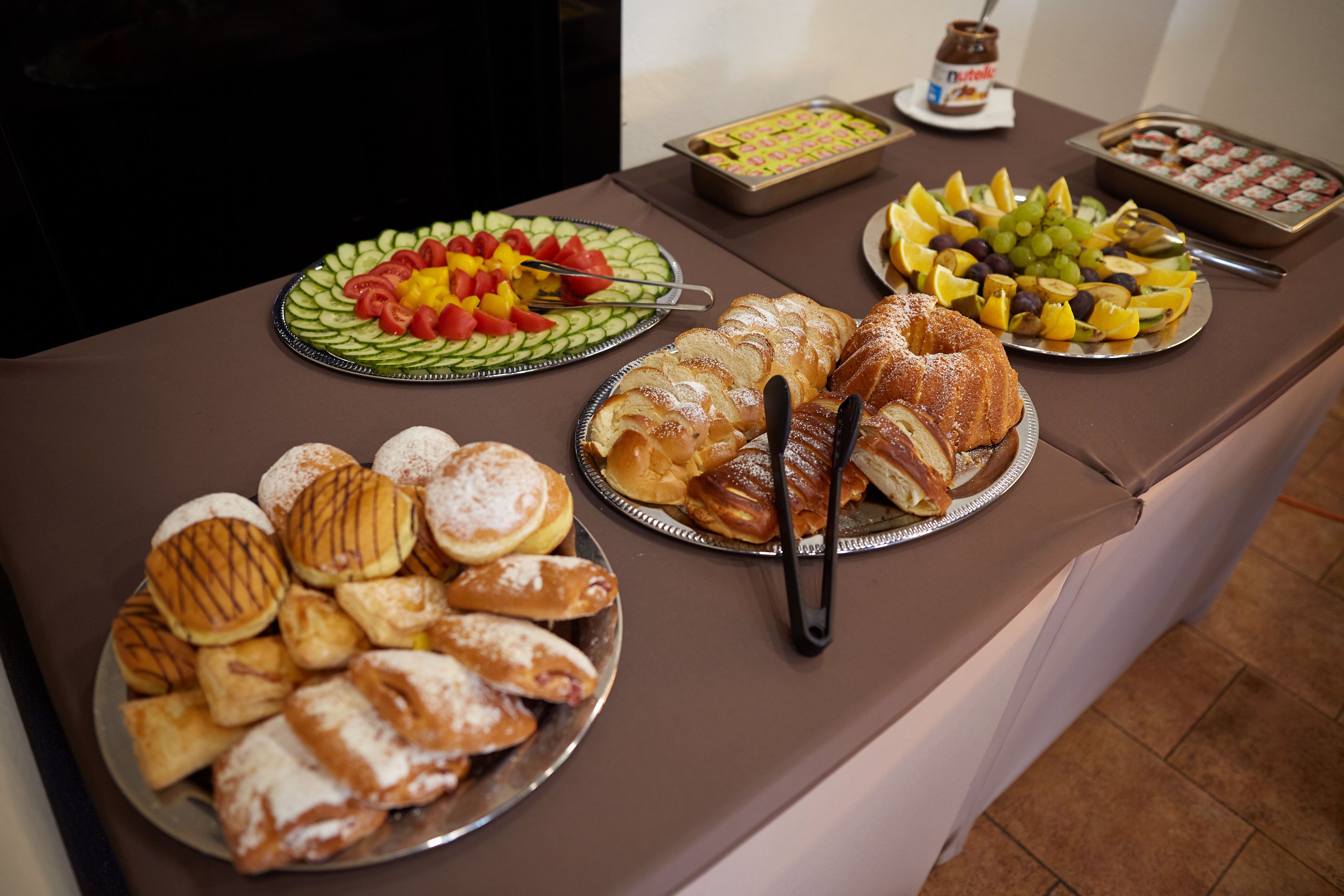 Une table de buffet proposant une variété d’aliments, notamment des pâtisseries, des fruits et des desserts.