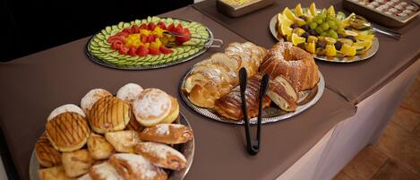 A buffet table with various food items including pastries, fruits, and desserts.
