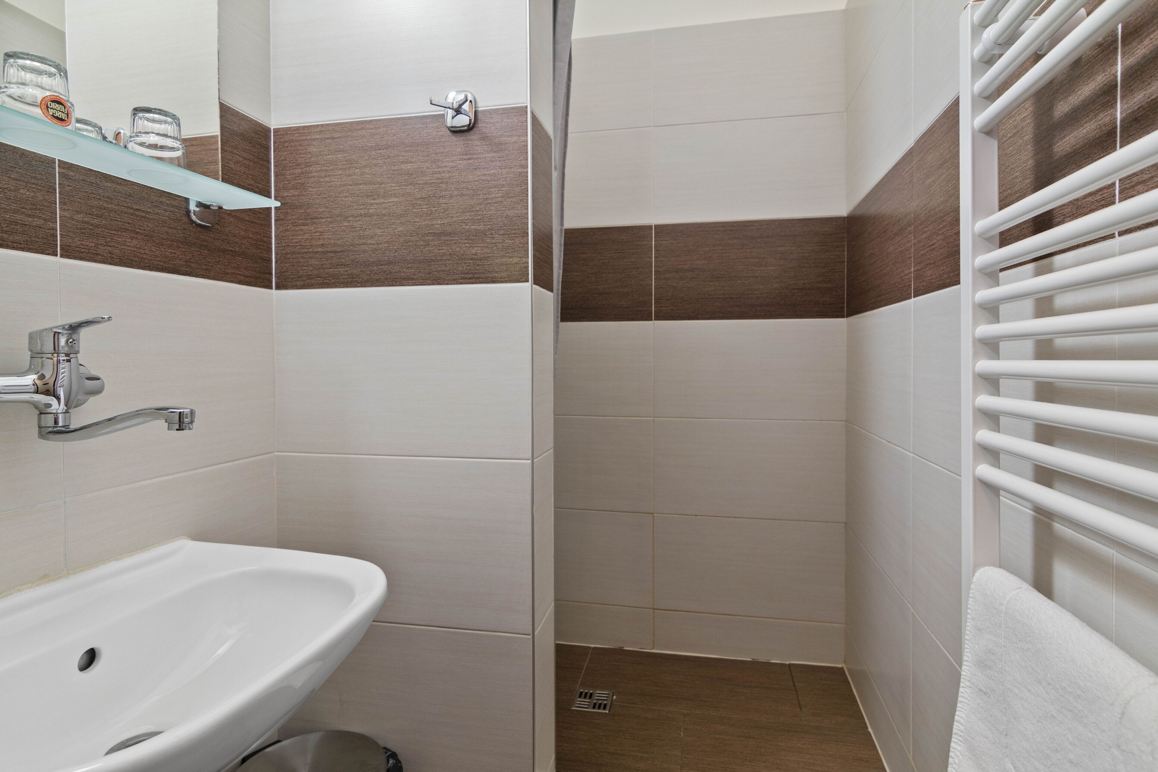 A bathroom with a white sink, a glass shower enclosure, and a towel rack.