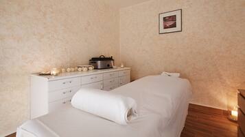 A bedroom with a bed, a dresser, a wall-mounted picture, and a lit candle on the floor.