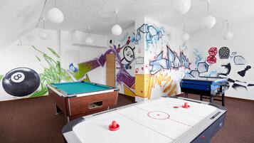 A recreational room with a pool table, foosball table, and a billiards table.