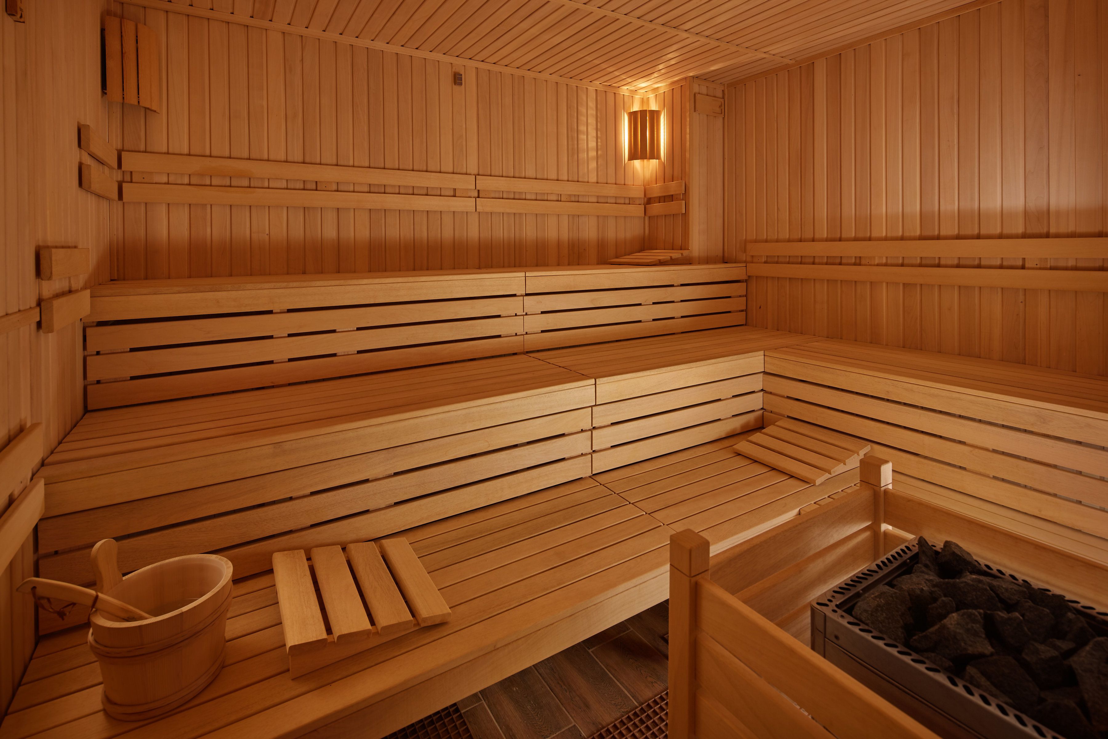 A sauna with wooden benches and a bucket.