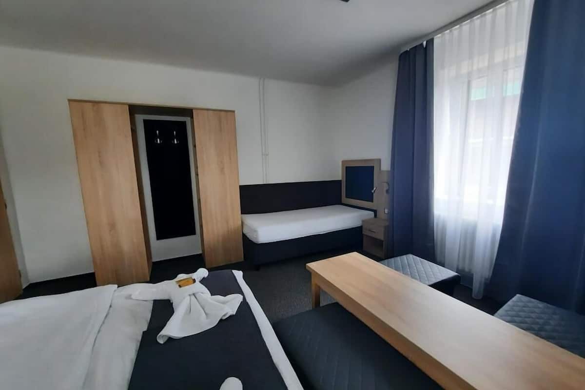 A hotel room with two beds, a desk, a TV, and a wardrobe.