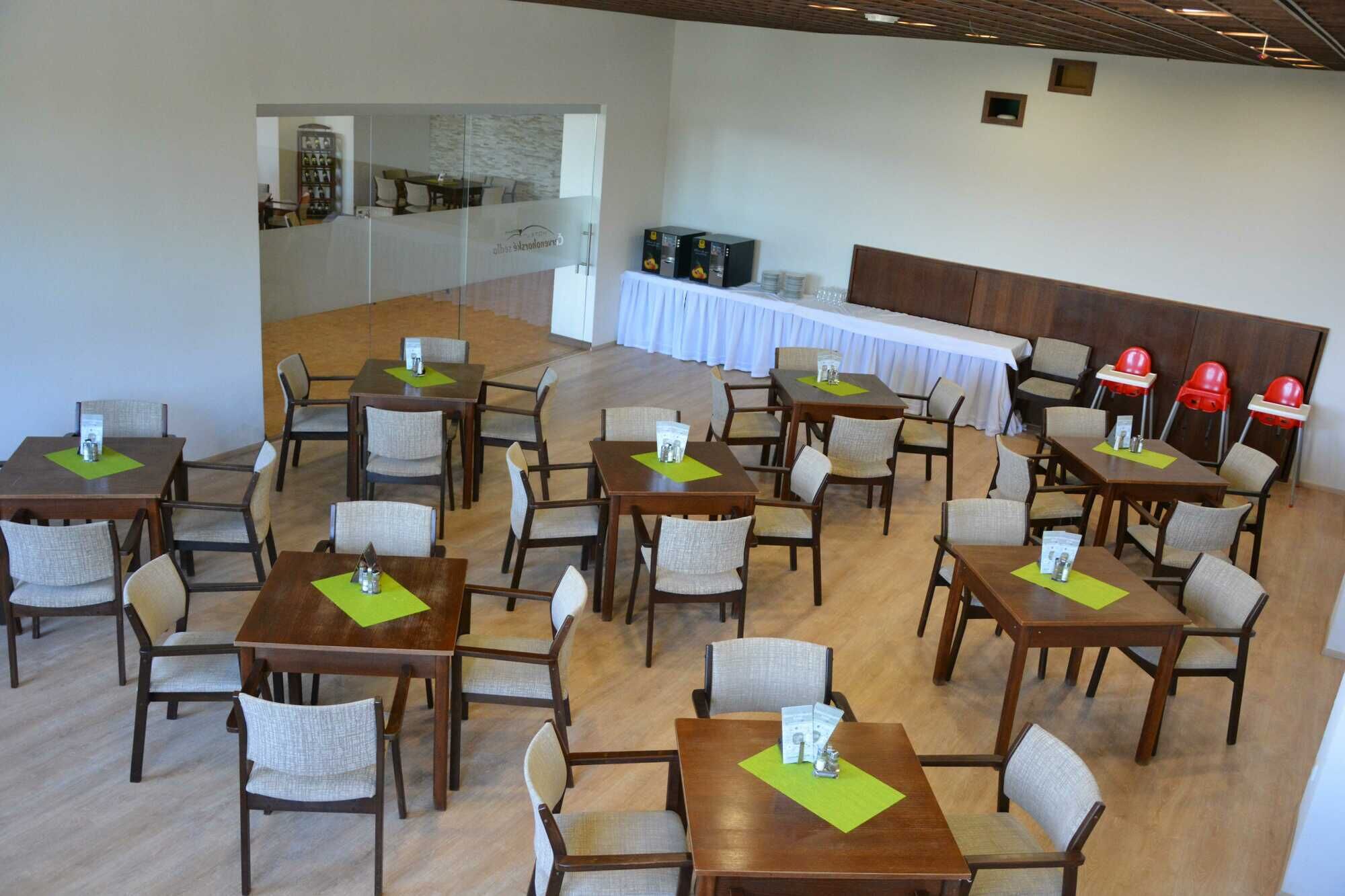 A spacious dining area with multiple tables and chairs, a white tablecloth-covered table, and a counter with beverages.