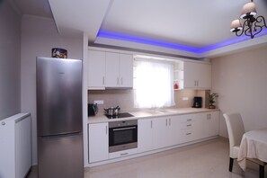 A modern kitchen with white cabinets, a Bosch refrigerator, an oven, and a sink.