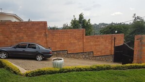 A car parked in a driveway with a brick wall and a metal gate. - Mubwiza Courts (Kigali)