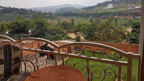 A balcony with a view of a green landscape and distant buildings. - Mubwiza Courts (Kigali)
