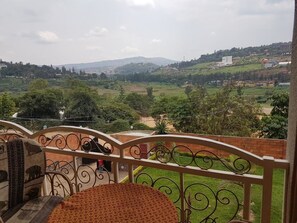 A balcony with a view of a green landscape and distant buildings. - Mubwiza Courts (Kigali)