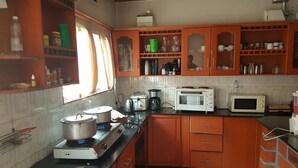 A kitchen with wooden cabinets, a gas stove, a microwave, and a toaster. - Mubwiza Courts (Kigali)
