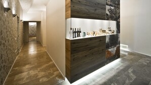 Un intérieur moderne avec un mur d’accent en bois, une étagère où sont exposées des bouteilles et un couloir orné de papier peint à motifs.