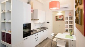 Una cocina moderna con armarios blancos, estufa a gas y un comedor con mesa y sillas blancas.